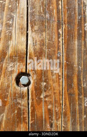 Rustic wooden planks with cracks and a single embedded bolt, perfect for backgrounds or carpentry themes. Stock Photo