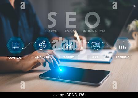 SEO workflow concept: marketer using tablet and laptop with interface icons for content, analysis, traffic and ranking. Modern office desk for search Stock Photo