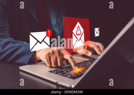 Hands typing on laptop with warning email envelopes and alert icons, showing concept phishing attack detection, suspicious inbox security, fraud preve Stock Photo