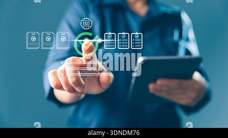 Digital document management, ISO compliance concept business professional approves checklists on virtual interface while holding tablet with file, aud Stock Photo