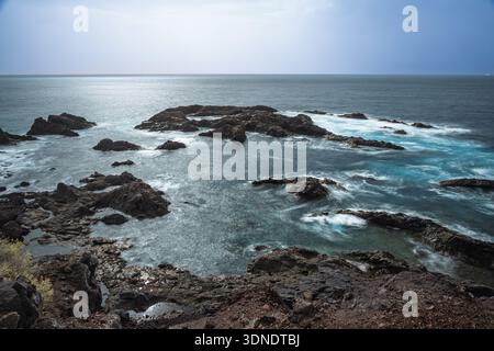 Daytime long exposure captures the smoothed waters and rugged volcanic rock formations along the dramatic Costa de Los Gigantes in Tenerife, Spain. Stock Photo