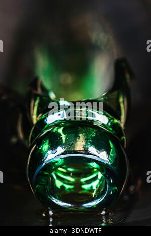 Close up of a shattered green alcohol bottle with focus on the broken neck and sharp glass fragments in a dark environment. Stock Photo