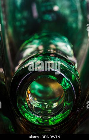 Close up of a shattered green alcohol bottle with focus on the broken neck and sharp glass fragments in a dark environment. Stock Photo