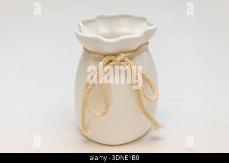 White ceramic vase tied with decorative rope on a light background Stock Photo