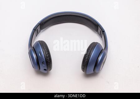 Blue wireless over ear headphones lie on a light isolated background Stock Photo