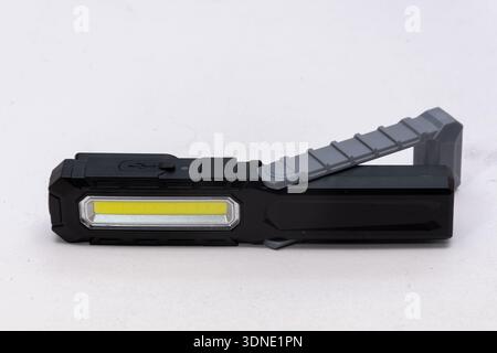 Folding work LED flashlight lies on a light isolated background Stock Photo