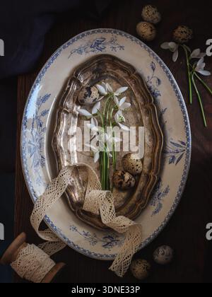 Dark mood Easter composition with spring flowers and quail eggs on a vintage plates Stock Photo