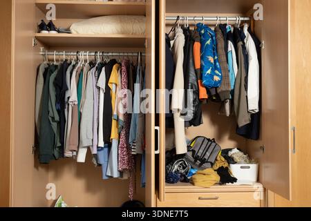 Family wardrobe organization with kids colorful jackets and adult clothes. Stock Photo