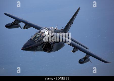 A Dassault-Dornier Alpha Jet A carrying Canadian registration C-GVTA, other marks 009 and serial 009 is captured in a close-up air-to-air view during a 2024 flight operated by Top Aces. The dual‑engine light attack and advanced trainer aircraft employs SNECMA/Turbomeca Larzac turbofan engines in a tandem crew cockpit. The image showcases canopy, fuselage contours, wings and twin nacelles. The Alpha Jet A supports pilot training missions and tactical simulations in contract adversary operations. Stock Photo
