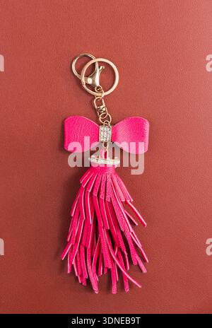 Trinkets with pink leather tassel for handbag, zipper or keyring with bead and puller on leather background Stock Photo