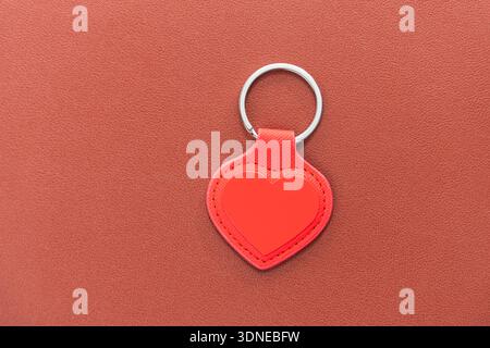 red leather heart shape keychain on leather background Stock Photo