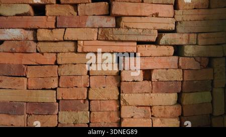 High resolution close-up of stacked terracotta bricks showing rough texture and uneven surfaces. Ideal for construction backgrounds, masonry themes Stock Photo