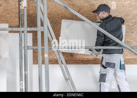 A worker is installing insulation panels on a construction site. Stock Photo