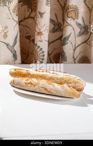Freshly baked assorted baguettes on white plate Stock Photo