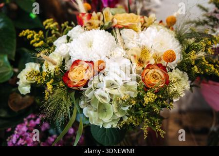 Vibrant mix of roses, hydrangeas, and chrysanthemums forms lush bouquet. Garden-style bouquet, wedding floral trends, natural aesthetics. Stock Photo