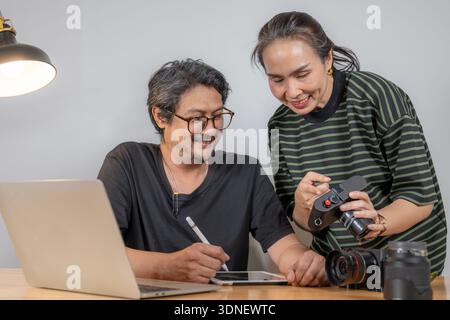 Two young photographers work together editing photos in a studio, reflecting teamwork, creativity, and a modern freelance lifestyle. Stock Photo