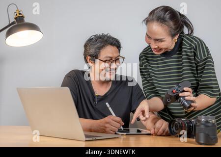 Two young photographers work together editing photos in a studio, reflecting teamwork, creativity, and a modern freelance lifestyle. Stock Photo