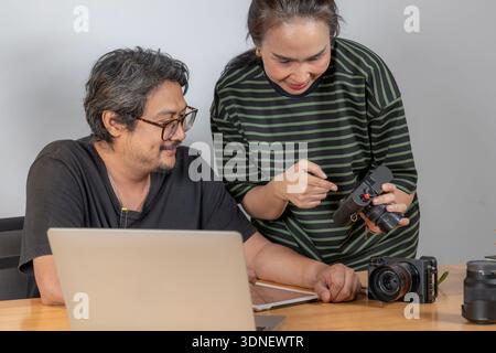 Two young photographers work together editing photos in a studio, reflecting teamwork, creativity, and a modern freelance lifestyle. Stock Photo