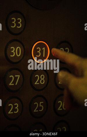 Hand pointing at highlighted number 31 on an elevator level panel, showing floor selection. Stock Photo