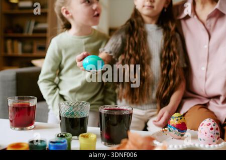Two Girls Decorating Easter Eggs Together Indoors with Adult Stock Photo