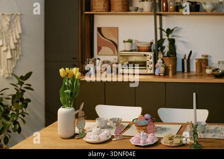 Easter Table Setting Featuring Sweets and Decorations in Cozy Kitchen Stock Photo