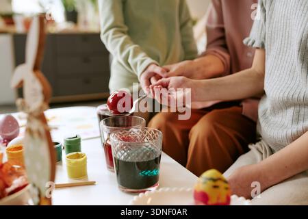 Woman and Child Coloring Easter Eggs Together at Home Table Stock Photo