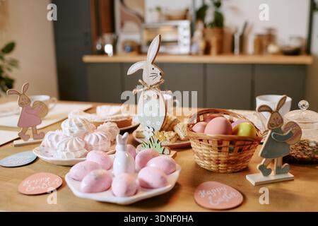Easter Table Displaying Decorative Bunny Figures and Basket with Colored Eggs Stock Photo