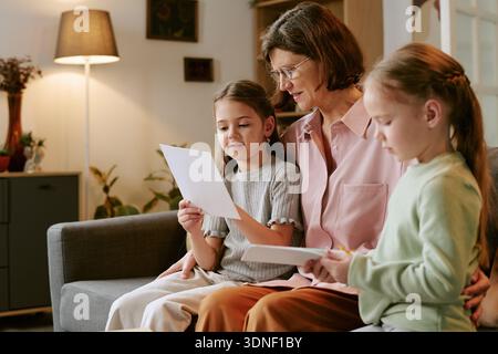 Middle Aged Woman Reading Letter with Two Girls Indoors Stock Photo