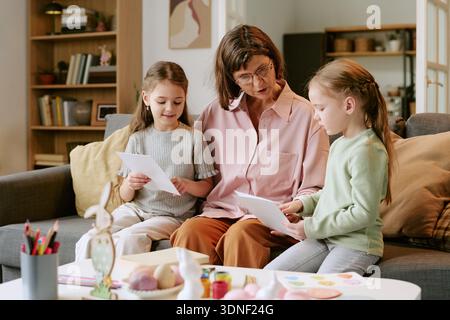 Middle Aged Woman Teaching Two Girls Reading Documents Stock Photo