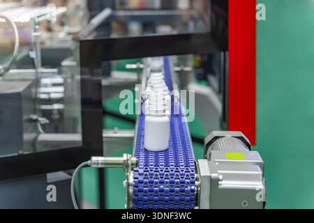 Moving polypropylene white bottles on conveyor belt of automatic liquid filling machine Stock Photo