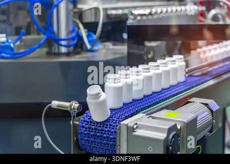 Moving polypropylene white bottles on conveyor belt of automatic liquid filling machine Stock Photo