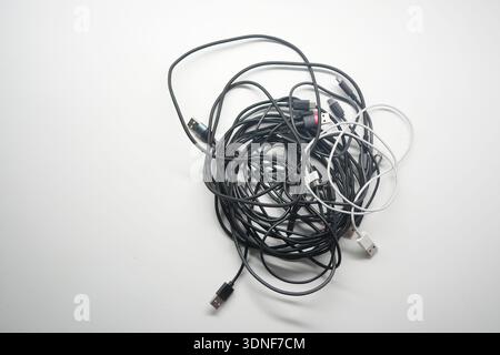 Multiple tangled charging cables on a white background Stock Photo