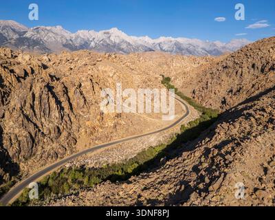 Aerial view of the winding road through lush green hills leading to the ...