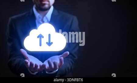 Man holds cloud symbol with arrows for file transfer in dark background Stock Photo
