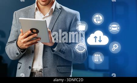 Businessman using a tablet with icons of technology in a modern office setting Stock Photo