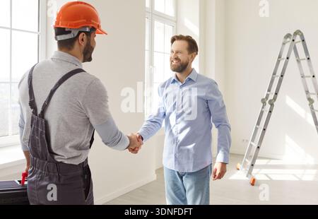 Contractor and client handshake sealing renovation agreement in bright apartment Stock Photo