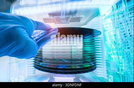 Gloved hand holding a Silicon Wafer in plastic holder box used in electronics for the fabrication of integrated circuits Stock Photo