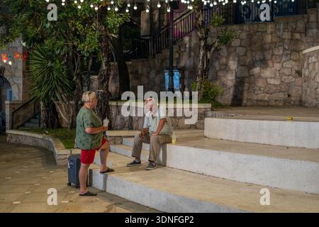 Senior Tourists Resting on Stone Steps at Night in Sunset Town Phu Quoc Stock Photo