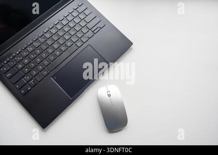 Laptop and mouse on a white table with copy space on the right. Stock Photo