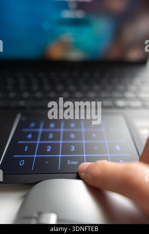 Man's hand pressing a backlit number pad on modern laptop. Stock Photo