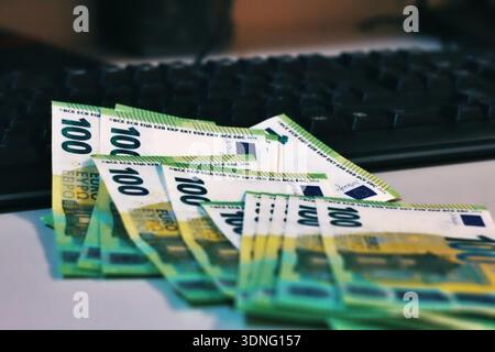 A close-up of a computer keyboard with euro banknotes resting on the keys, symbolizing digital work and earned income. Stock Photo