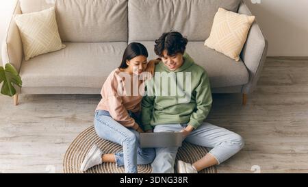 Young Couple Sitting on Floor Using Laptop in Living Room During Daytime Stock Photo