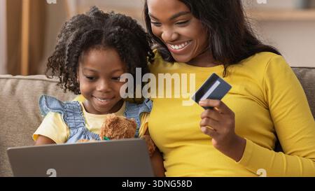 Mother and Daughter Share Shopping Experience While Using Laptop at Home Stock Photo