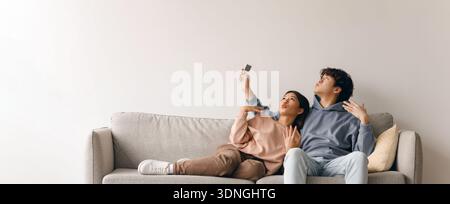 Couple Sharing a Moment While Taking a Selfie on a Sofa in a Cozy Living Room Stock Photo