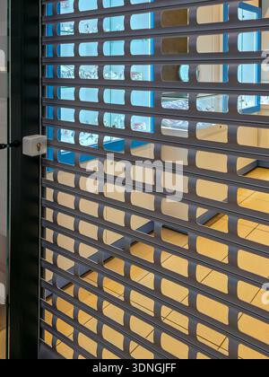 Jewelry store closed with metal roller shutter partially lowered, revealing bright showcases inside, symbolizing retail security, luxury, protection Stock Photo
