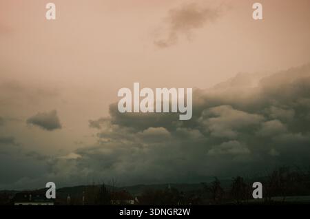Dramatic storm clouds gather over a quiet European village at dusk Stock Photo