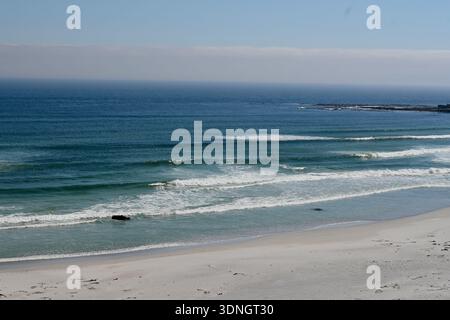 Gentle ocean waves rolling onto a quiet sandy beach under clear sky along the South African coastline. Stock Photo