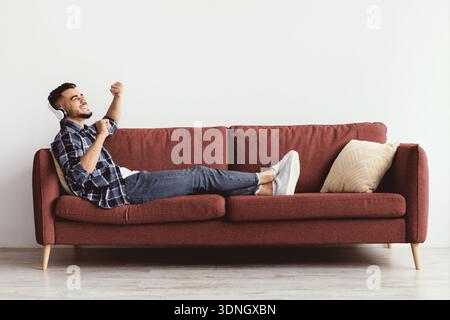 Man Listens to Music on Couch and Enjoys the Moment in an Indoor Space Stock Photo