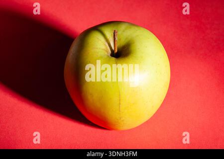 yellow apple on red background Stock Photo