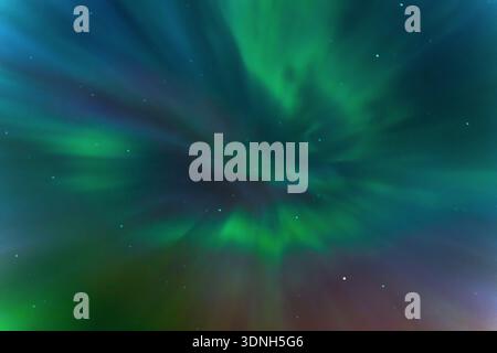 Colorful northern lights background on a dark night. Abstract, swirling patterns of auroral light. Stock Photo